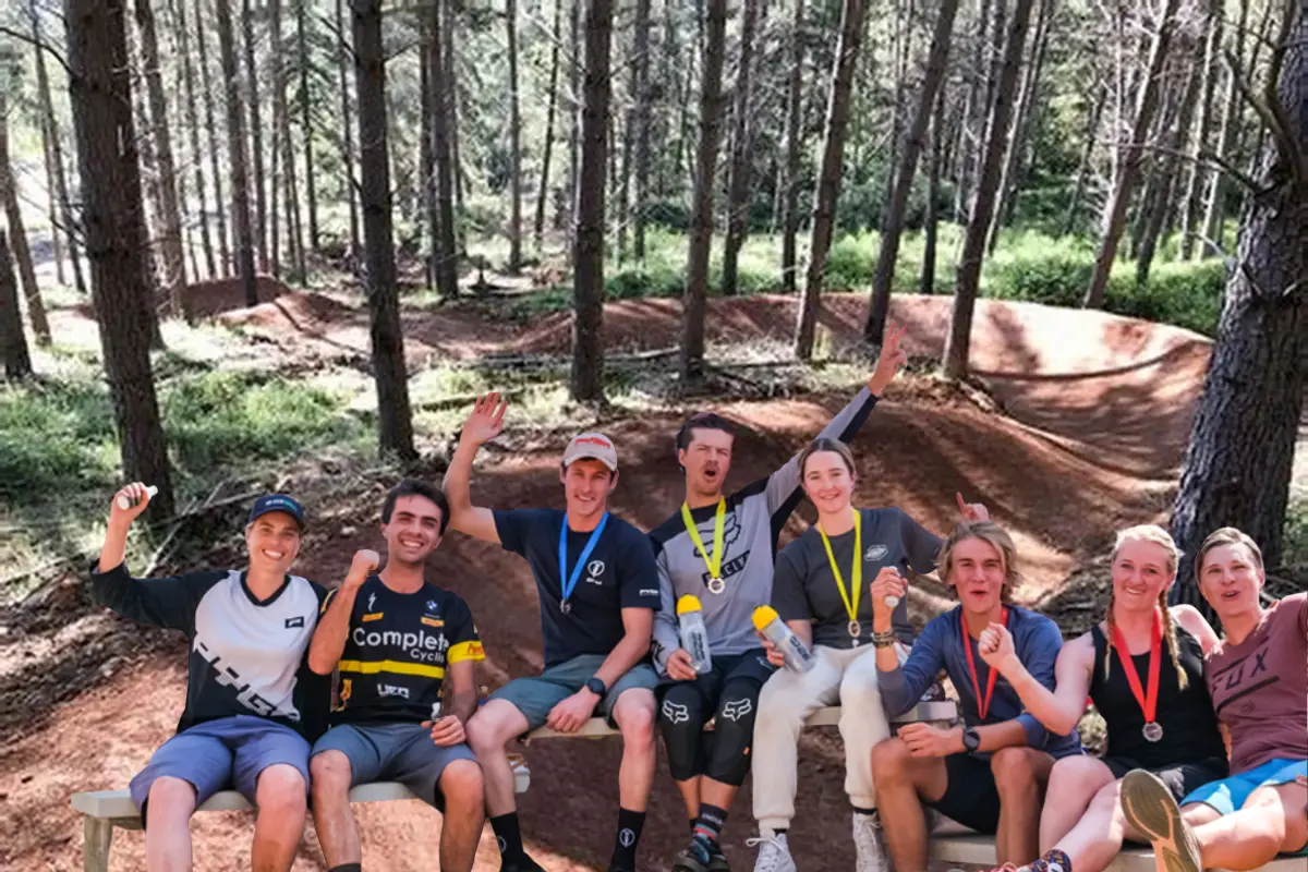 Smiling enduro riders with medals posing in front of a Gauteng Cycling Series backdrop.
