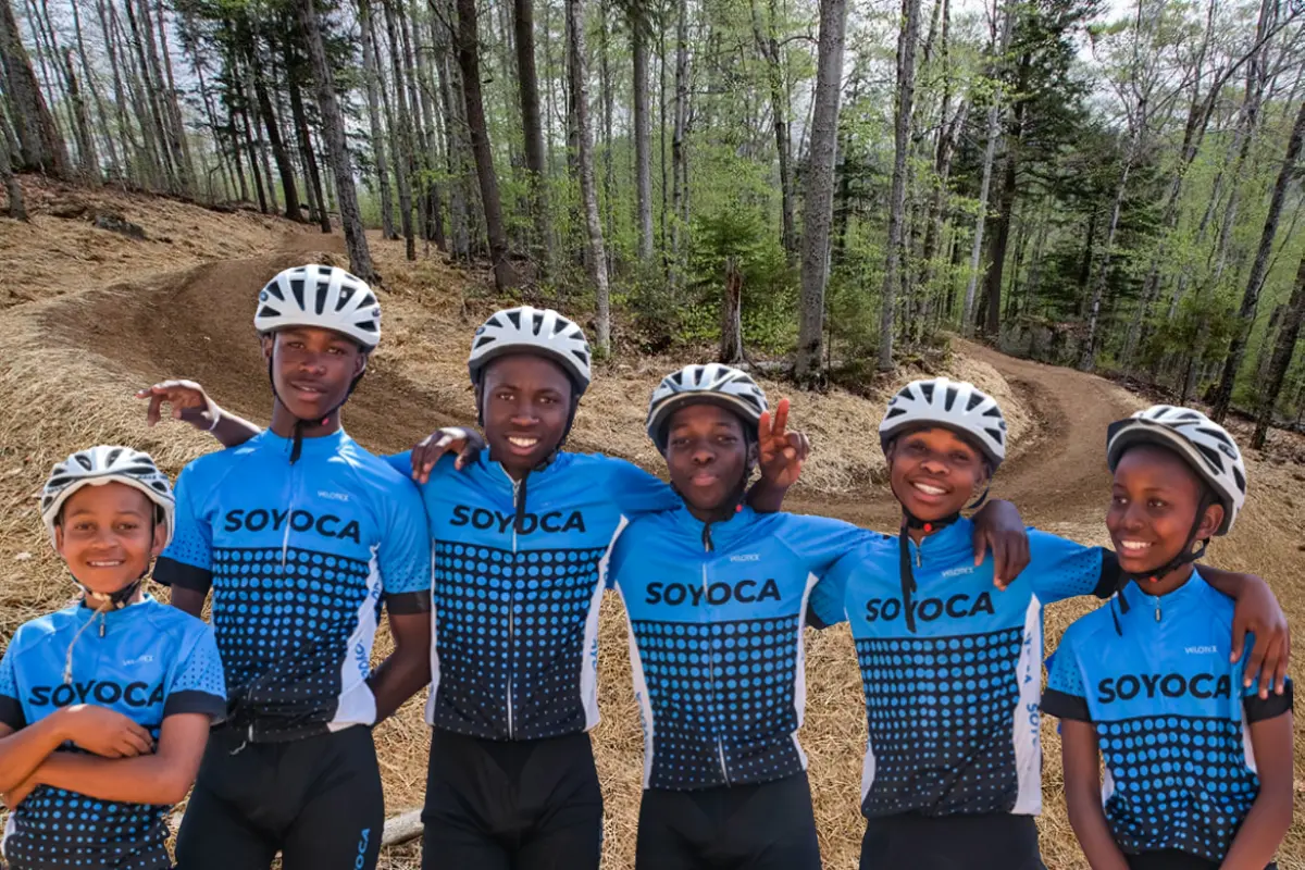 Smiling youth cyclists in blue SOYOCA kit posing in front of a Gauteng Cycling Series backdrop.