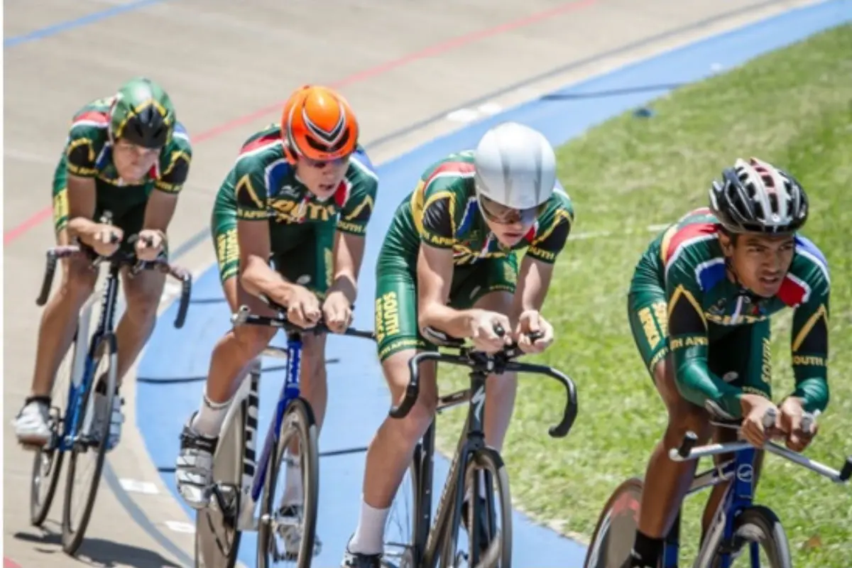 South African junior track cyclists in aero position on a velodrome, riding in close formation.